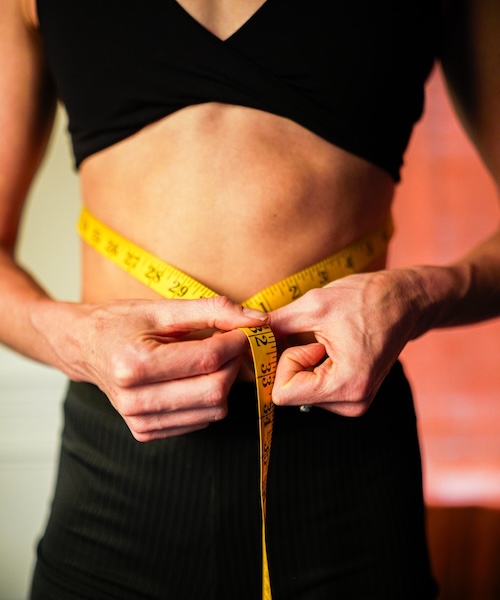 woman measuring her waist with a tape measure